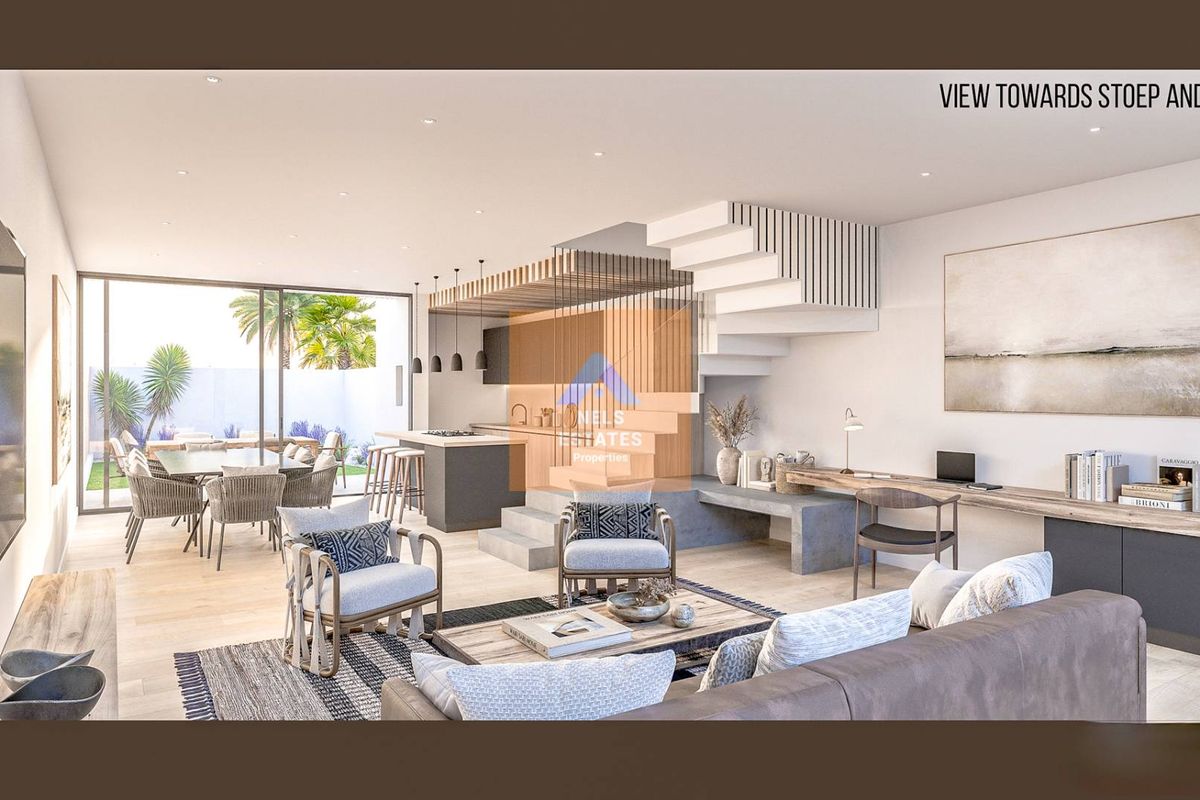 Modern open-plan living area featuring a sleek kitchen, integrated staircase, and seamless flow to the outdoor patio and garden through large sliding doors.