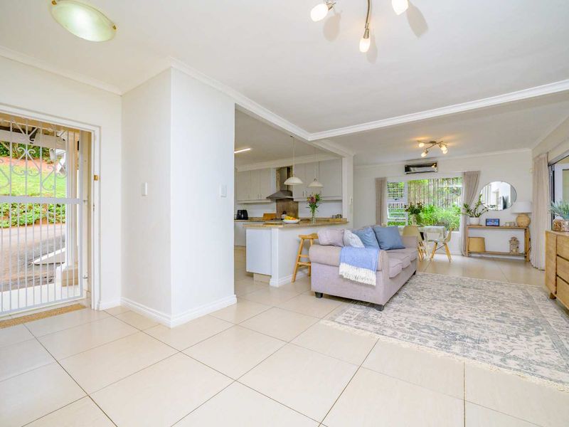 Open plan living and kitchen area featuring tiled floors, modern cabinetry, and direct access to the exterior through a security gate.