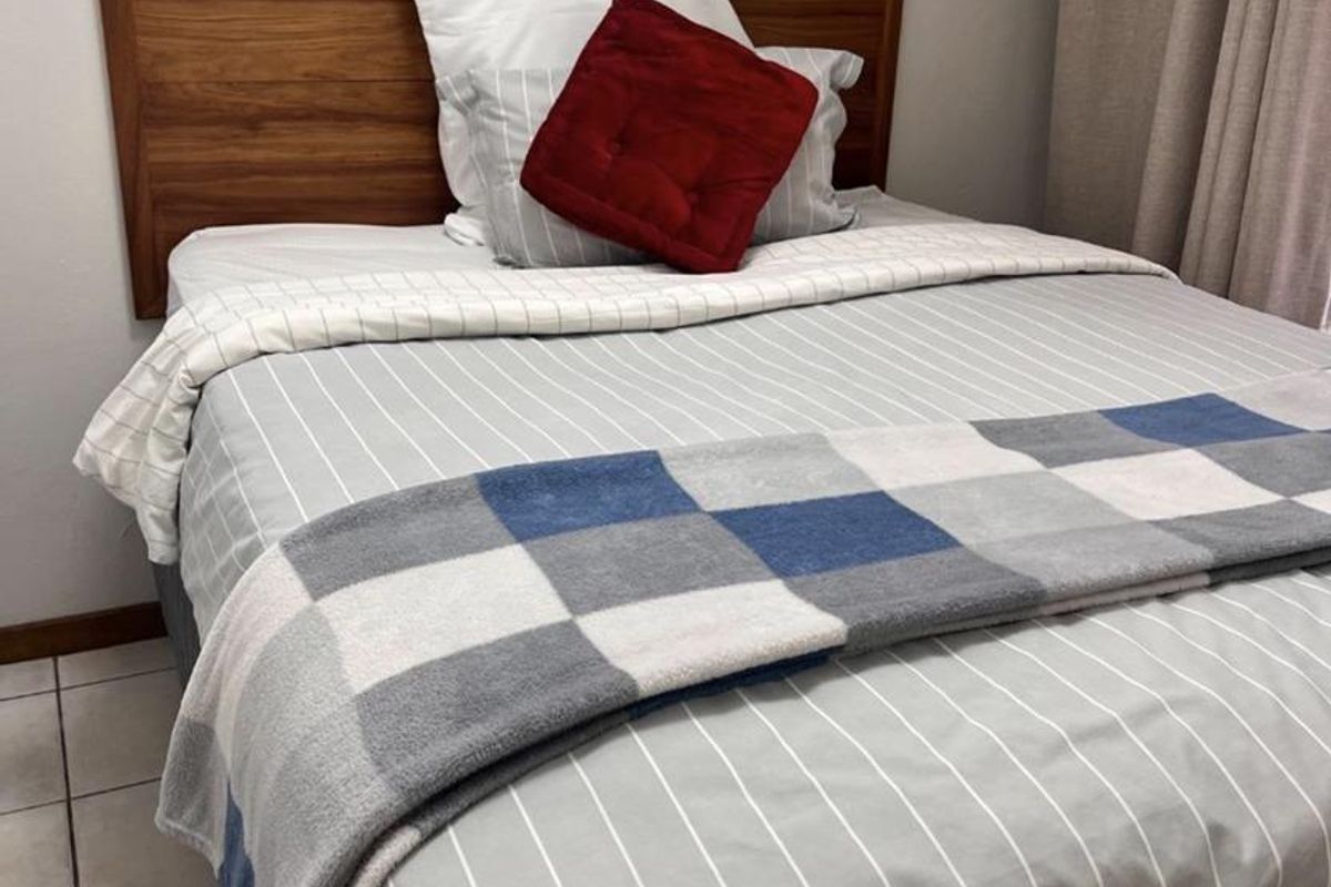A bedroom featuring tiled flooring and a built-in wooden headboard.