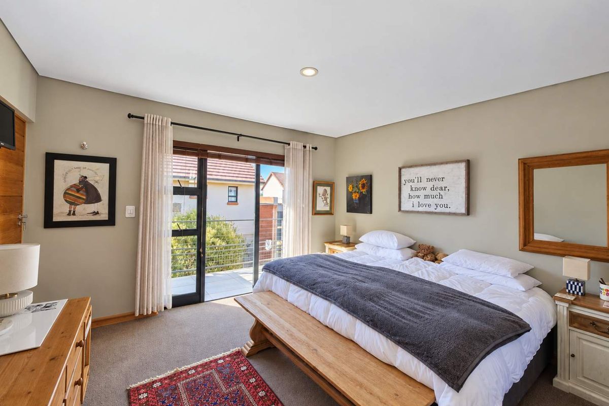 A well-maintained bedroom featuring neutral walls, carpeted flooring, and a sliding glass door providing direct access to a private balcony.