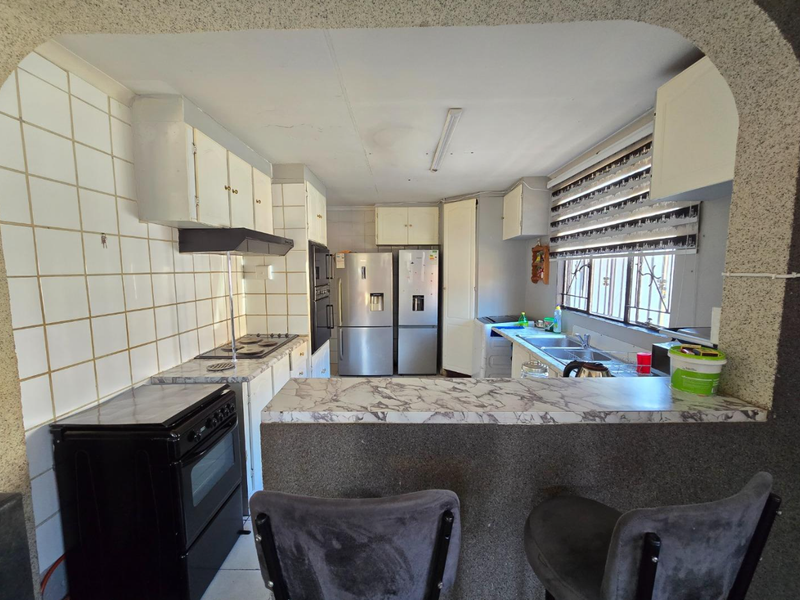 A functional kitchen featuring built-in cabinetry, laminate countertops, a breakfast bar, and integrated cooking appliances, offering potential for modernization.