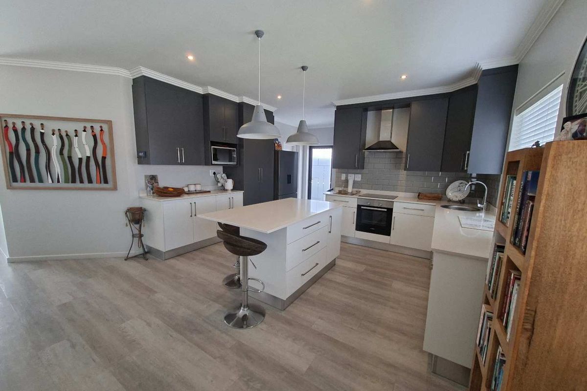 Modern kitchen featuring a central island, quartz countertops, subway tile backsplash, built-in appliances, and contemporary two-tone cabinetry.
