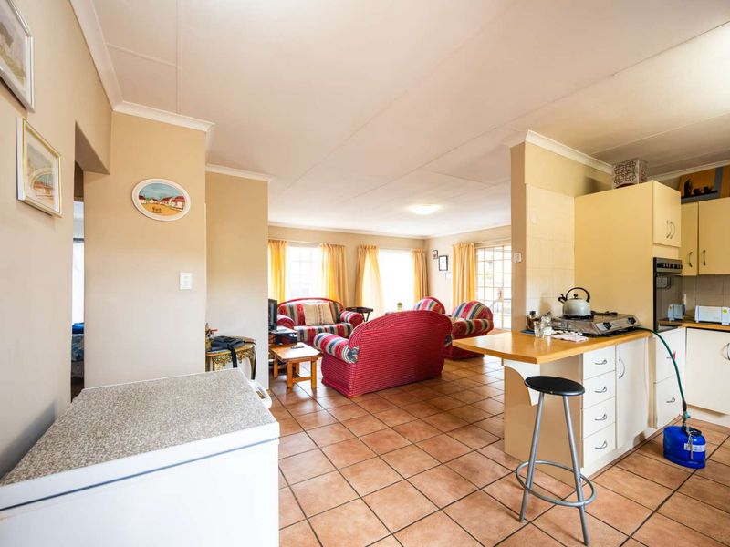 Open-plan living and kitchen area featuring tiled flooring, built-in cabinetry, and a breakfast bar, creating a functional and connected living space.