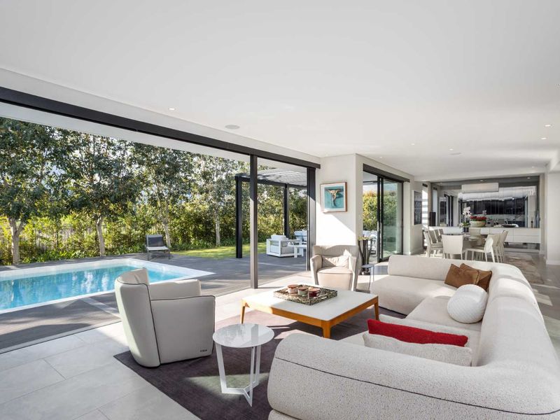 Spacious open-plan living area featuring seamless indoor-outdoor flow through large sliding glass doors to a private swimming pool and deck.