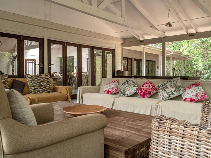 Spacious covered patio featuring exposed timber roof trusses and large timber-framed glass folding doors, offering a seamless transition to the outdoor garden area.