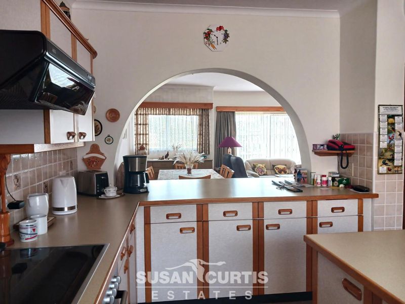 Open plan kitchen featuring built-in cabinetry and laminate countertops, connected to the living and dining area through a feature archway.