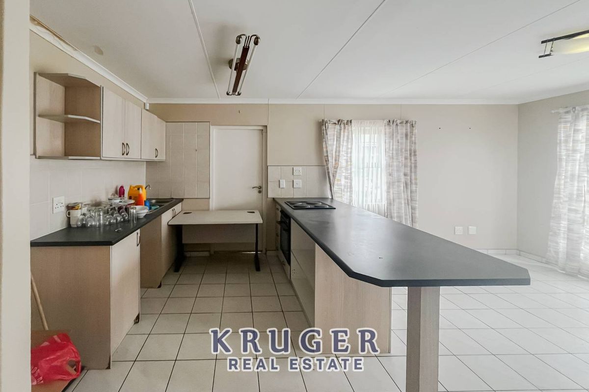 Functional kitchen featuring a breakfast bar, built-in hob, and tiled flooring, offering a practical layout for daily meal preparation.