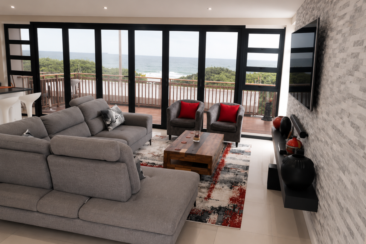 Modern living room featuring a stone accent wall, large sliding doors opening to a balcony with ocean views, and sleek tiled flooring.