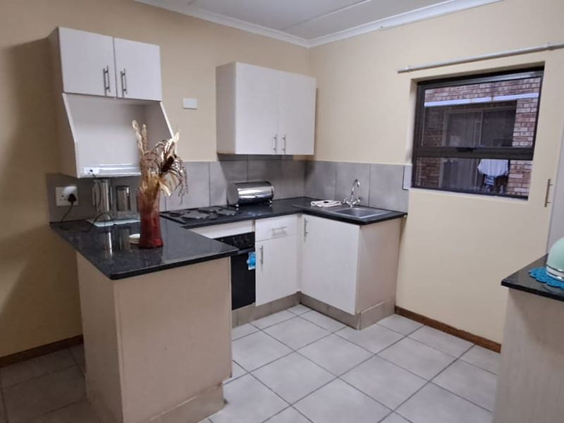 A functional kitchen featuring built-in cabinetry, granite countertops, a built-in oven and hob, and tiled flooring.