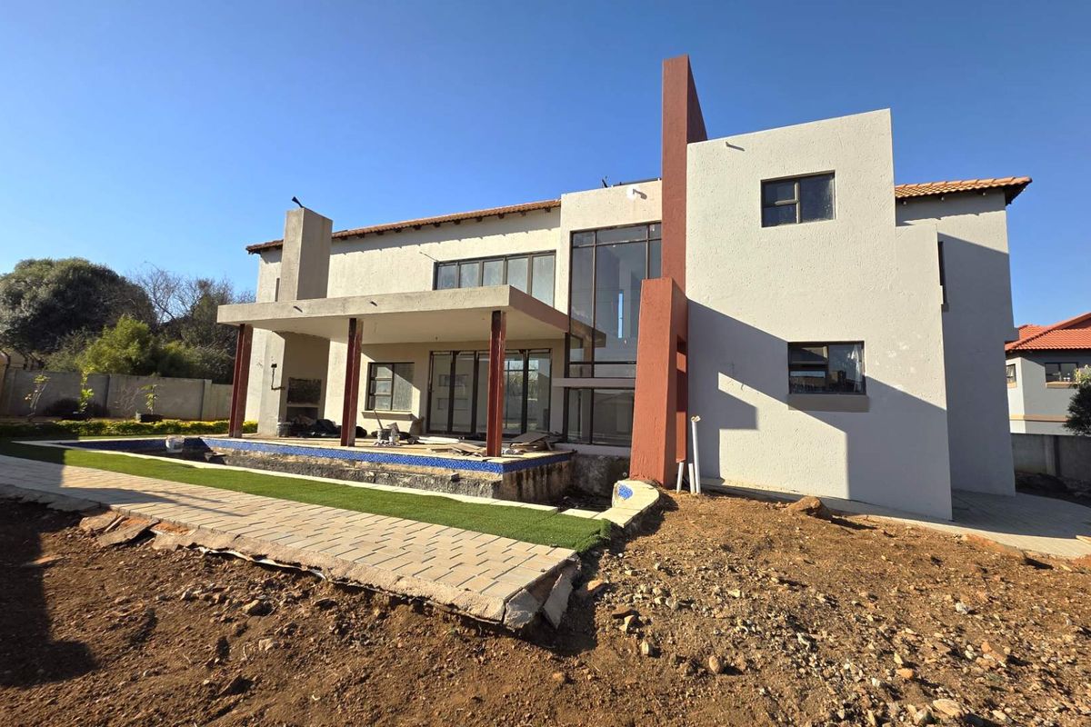 Rear view of a modern double-story house featuring a covered patio, swimming pool, and unfinished landscaping, offering significant potential for outdoor completion.