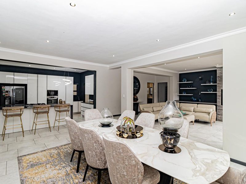 Spacious open-plan living area featuring a modern kitchen with island, dining space, and lounge, finished with high-quality tiling and contemporary lighting.