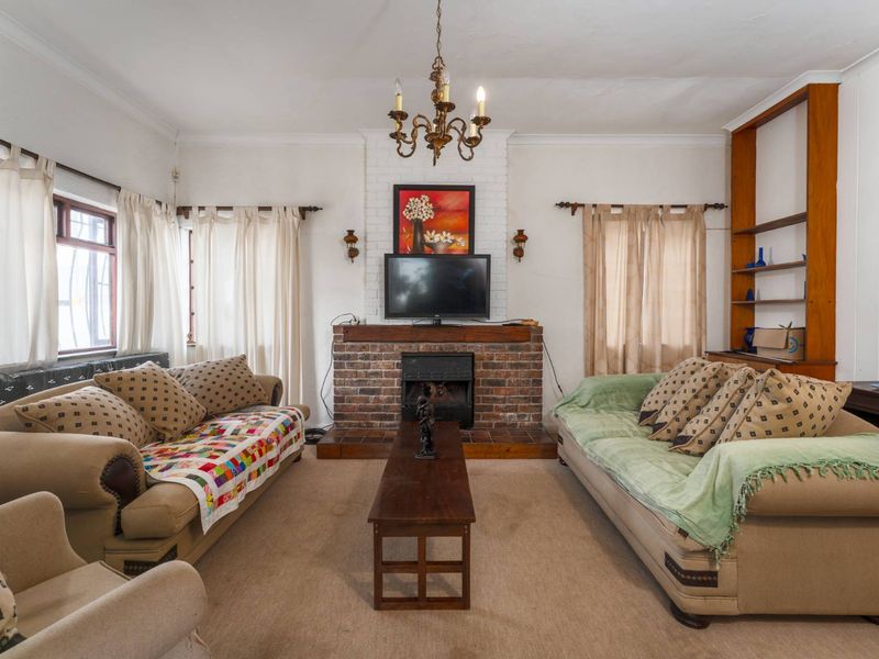 A cozy living room featuring a central brick fireplace with a tiled hearth and built-in wooden shelving.