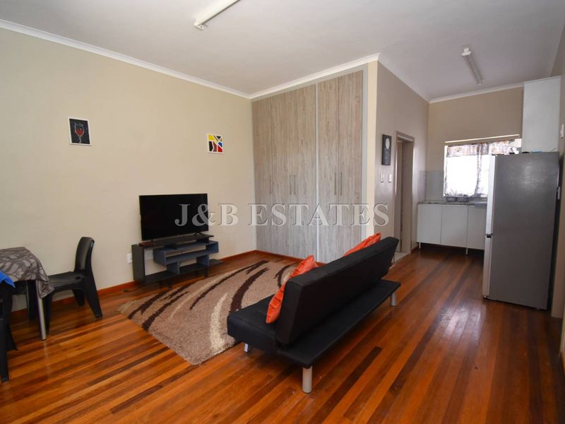 Open plan living area featuring polished timber flooring, built-in cabinetry, and an integrated kitchenette space.