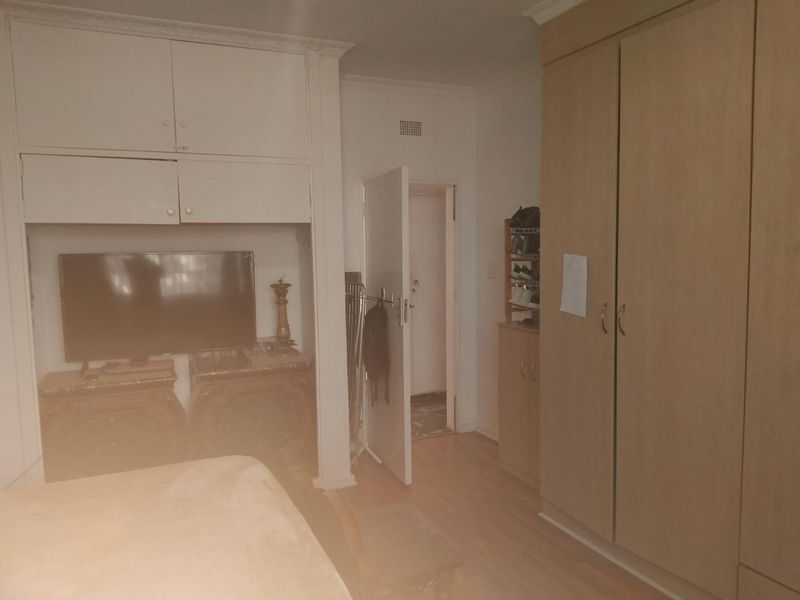 A bedroom featuring built-in cupboards, laminate flooring, and ceiling cornice, providing functional storage and a neutral base for interior updates.