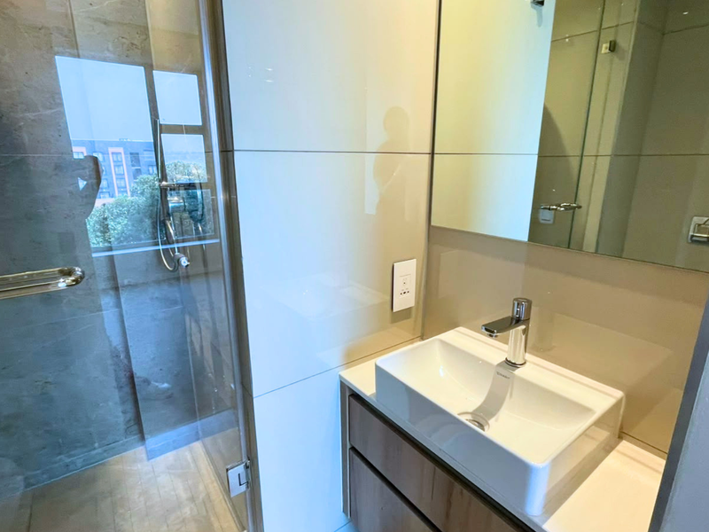 Modern bathroom featuring a glass-enclosed shower, sleek wall-mounted vanity with a vessel sink, and large wall mirror.