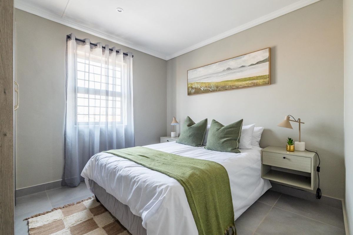 A well-maintained bedroom featuring neutral wall tones, tiled flooring, and a window with natural light.