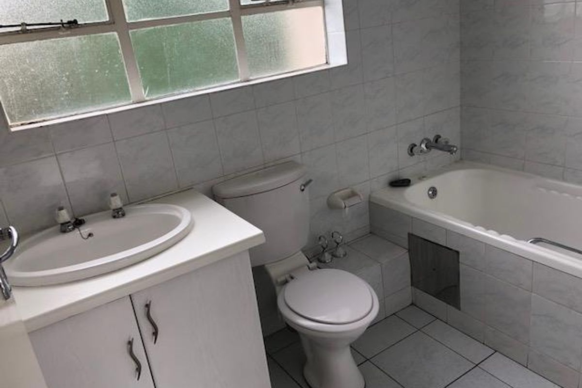A functional bathroom featuring a built-in vanity, toilet, and bathtub with tiled walls and flooring.
