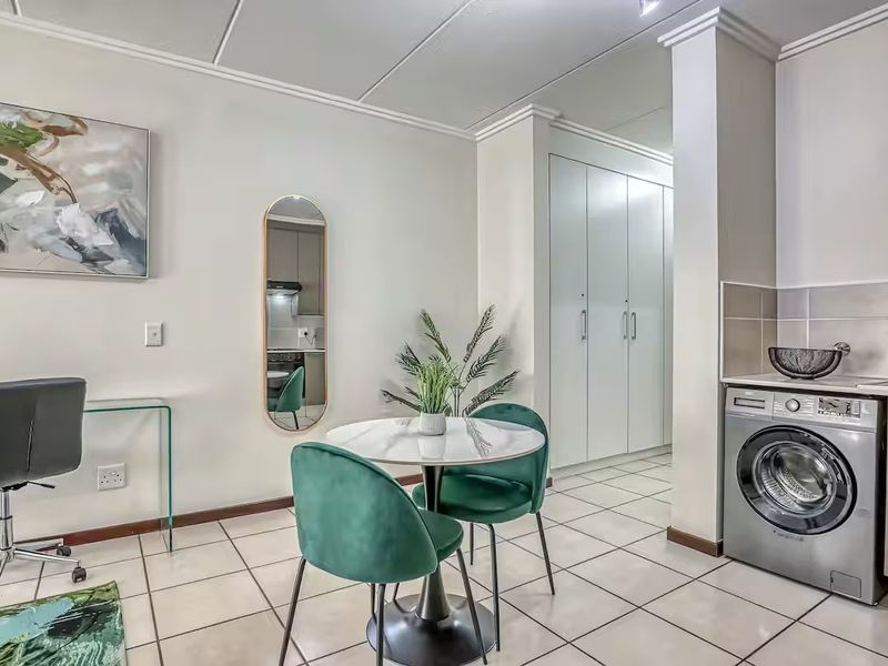 Open-plan living area featuring tiled flooring, built-in storage cupboards, and a dedicated laundry space with integrated plumbing connections.