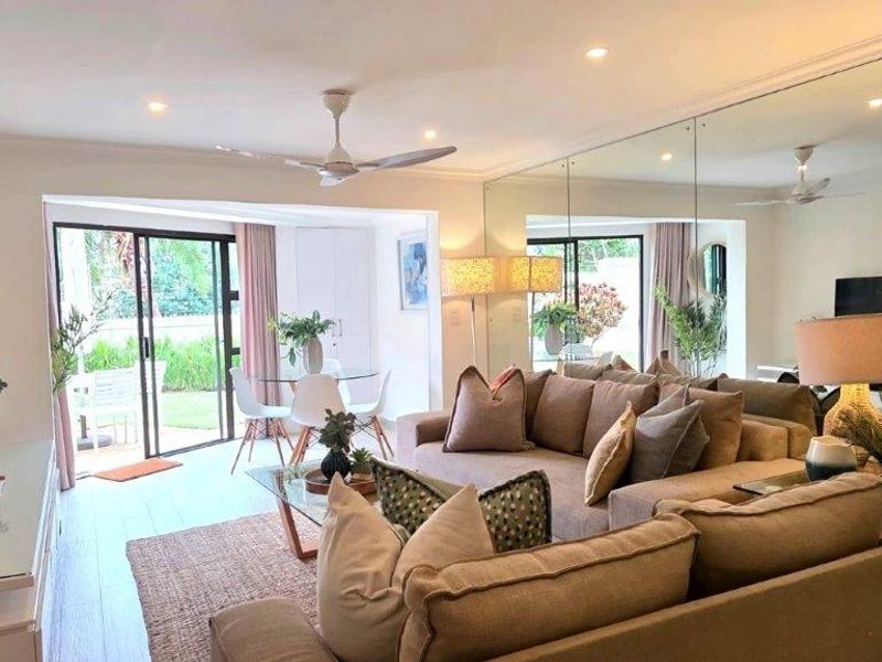 Bright open-plan living area featuring tiled floors, recessed lighting, a ceiling fan, and a large mirrored wall, with direct access to an outdoor patio.
