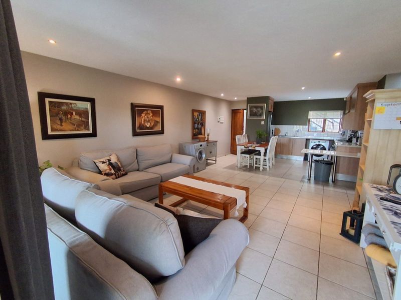 Open-plan living and kitchen area featuring tiled flooring, recessed lighting, and functional kitchen cabinetry with integrated appliances.