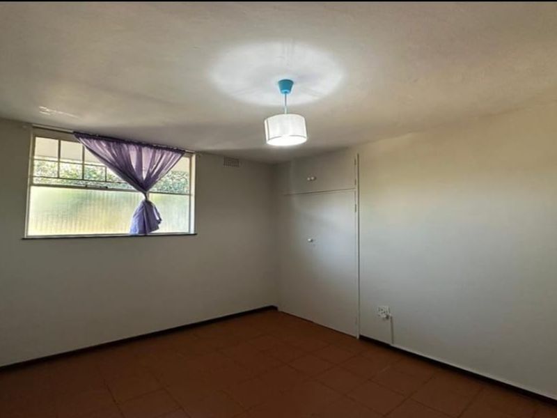 A vacant bedroom featuring tiled flooring, a built-in cupboard, and a central ceiling light fixture.