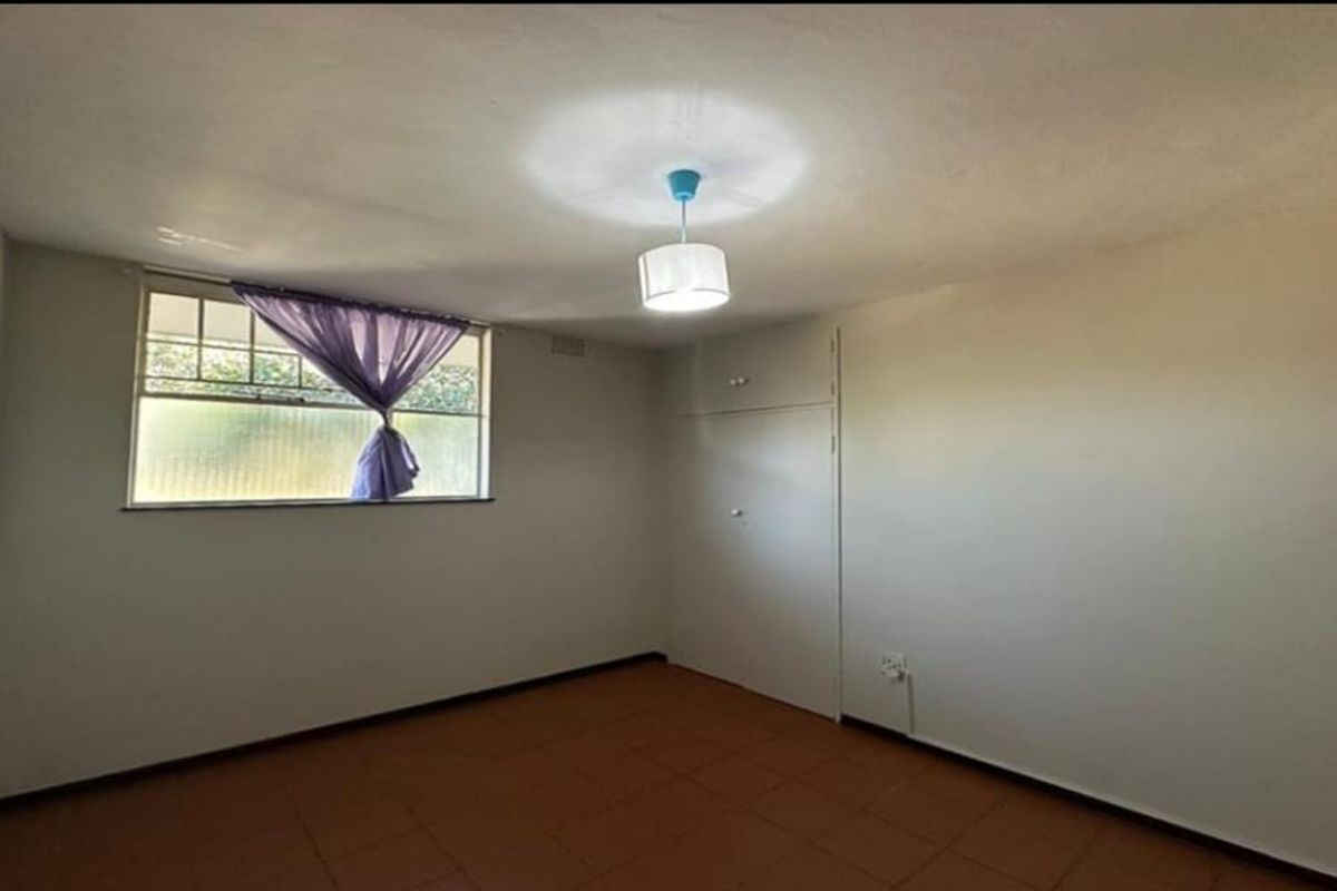 A vacant bedroom featuring tiled flooring, a built-in cupboard, and a central ceiling light fixture.