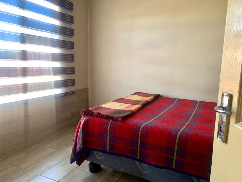 A simple bedroom featuring tiled flooring and modern zebra blinds, offering a neutral base for personalization.