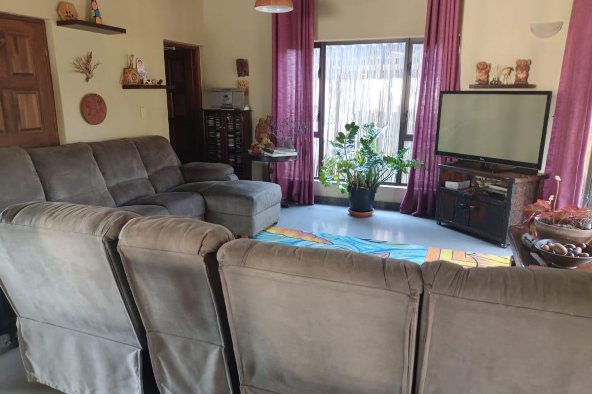 A comfortable living room featuring a large window with natural light, neutral walls, and a functional layout suitable for relaxation.