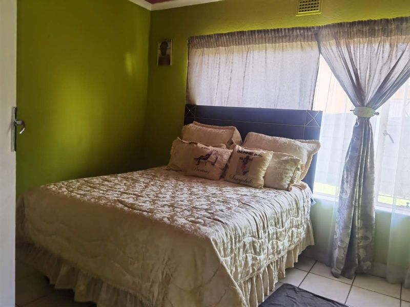A bedroom featuring tiled flooring, a built-in headboard, and a ceiling vent, with green painted walls.