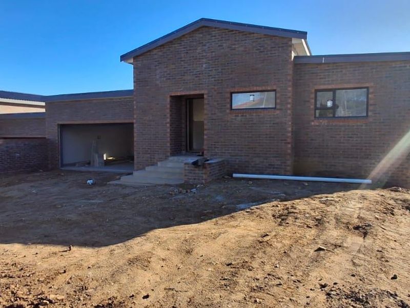 Front view of a newly constructed face brick house featuring a garage and unfinished exterior grounds.