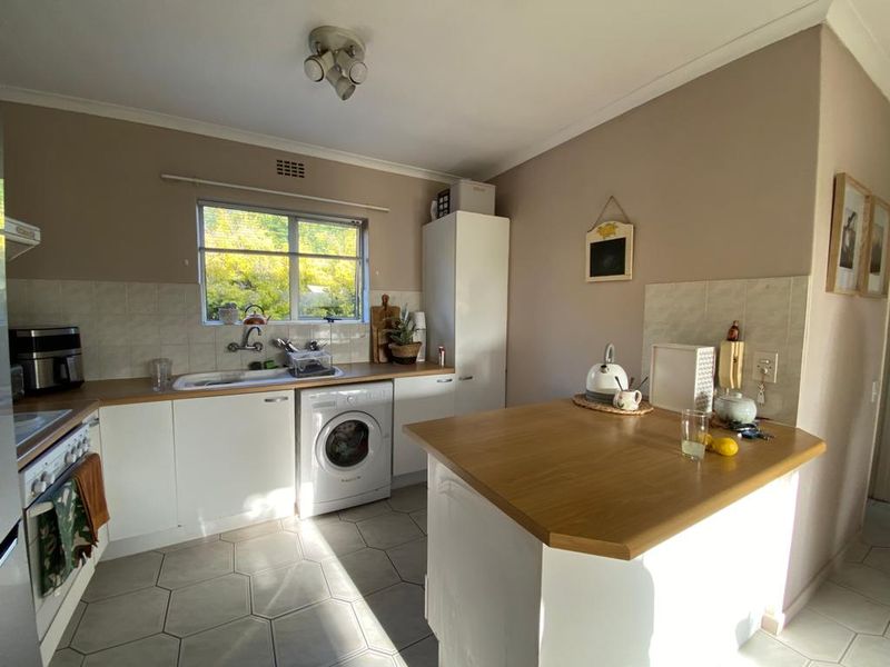 Functional kitchen featuring white cabinetry, wood-look laminate countertops, a built-in breakfast bar, and tiled flooring with a convenient integrated laundry space.
