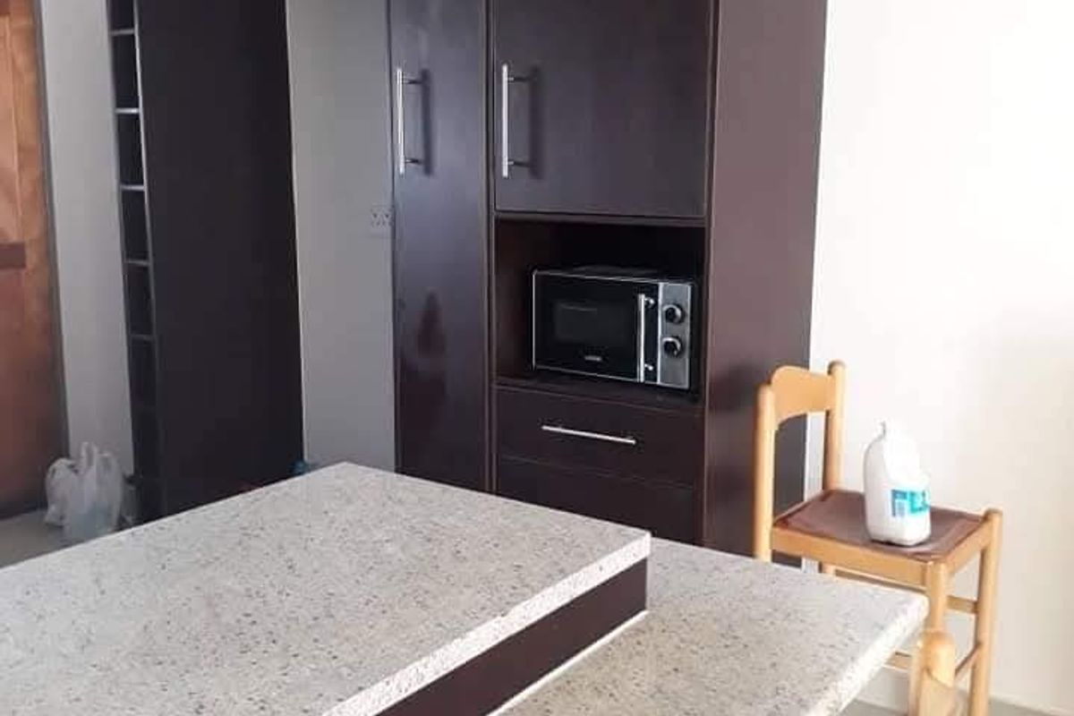 A kitchen area featuring dark wood built-in cabinetry, a stone-topped island or breakfast bar, and tiled flooring.