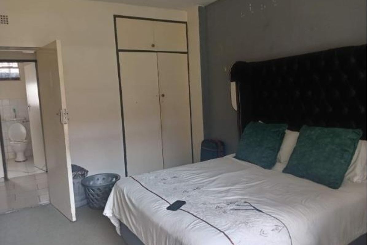A bedroom featuring built-in cupboards and direct access to an en-suite bathroom, requiring cosmetic updates to improve the overall finish.