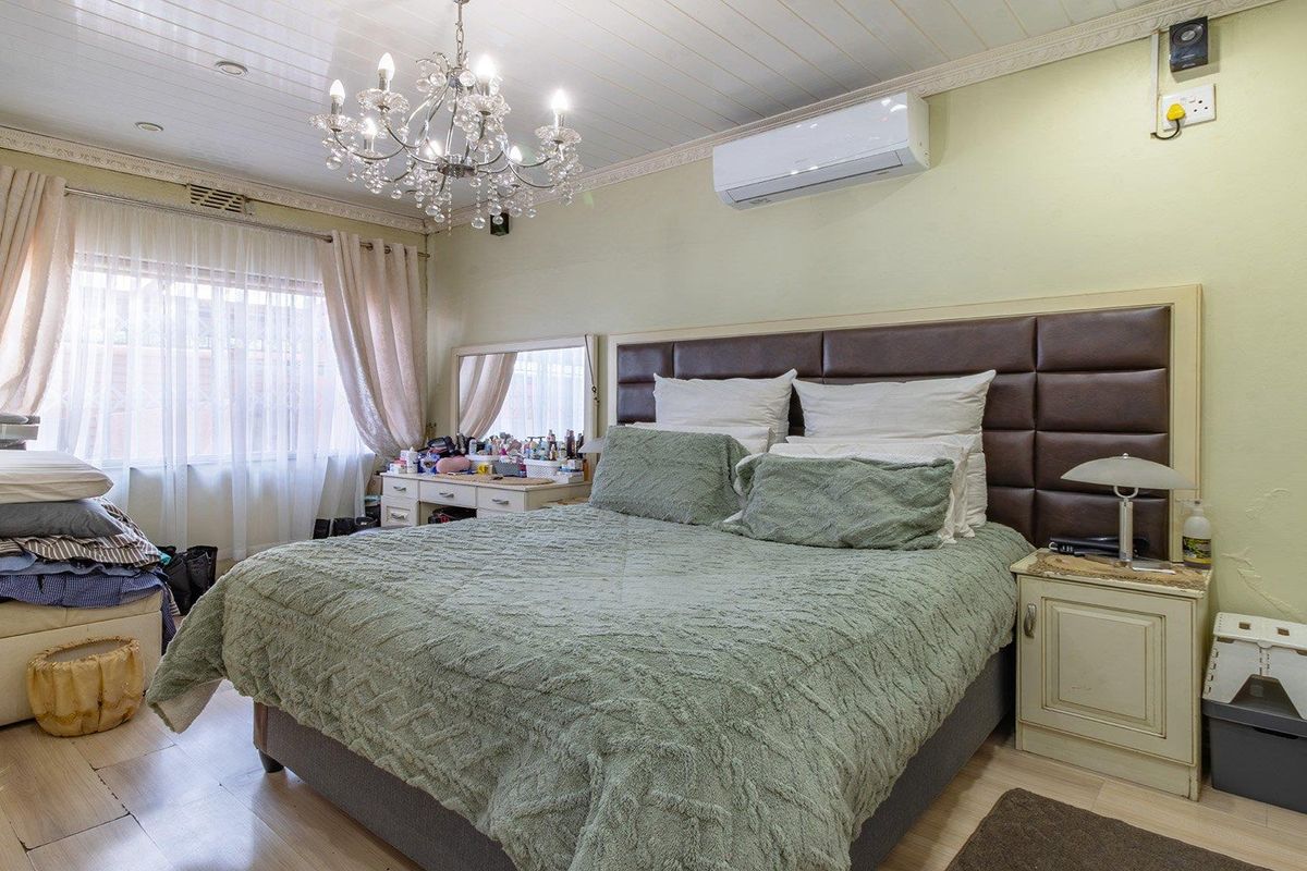 A bedroom featuring a tongue-and-groove ceiling, split-system air conditioning, and a built-in headboard, offering a functional space with classic architectural details.