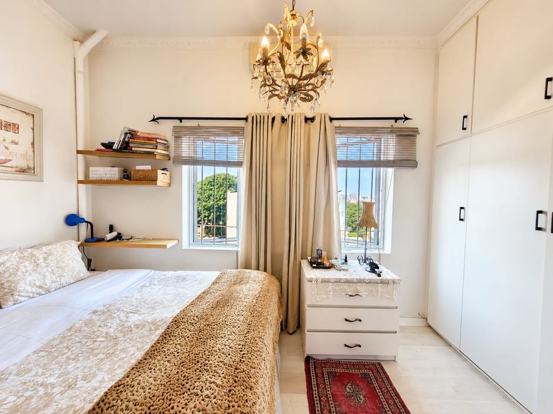 A well-lit bedroom featuring built-in floor-to-ceiling wardrobes, floating shelving, and decorative crown molding, providing ample storage and a classic aesthetic.