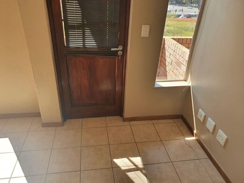 An empty living area featuring tiled flooring, a timber door, and neutral wall finishes, offering a blank canvas for interior design.