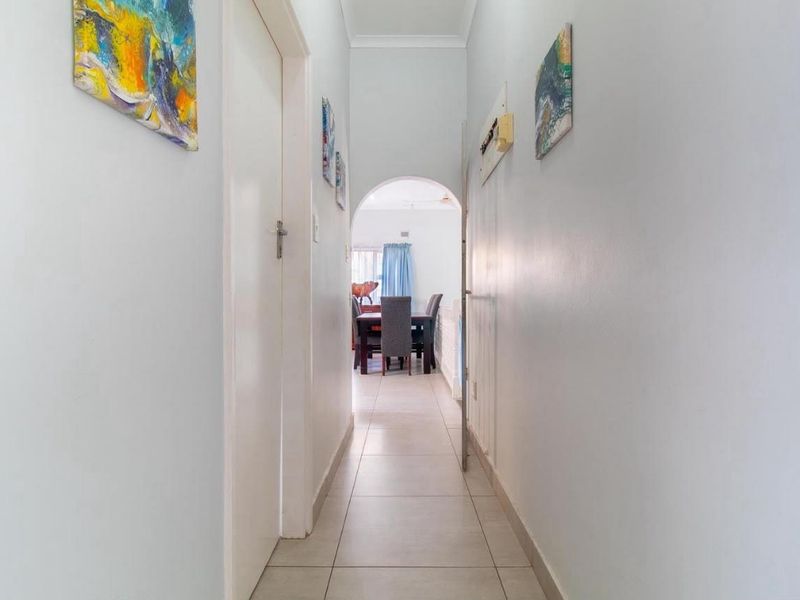 A bright, tiled hallway featuring an arched doorway leading into the dining area, providing a clean transition between living spaces.