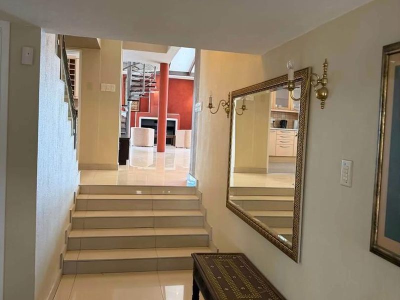 A bright hallway featuring tiled flooring and a staircase leading to an open-plan living area with a spiral staircase.