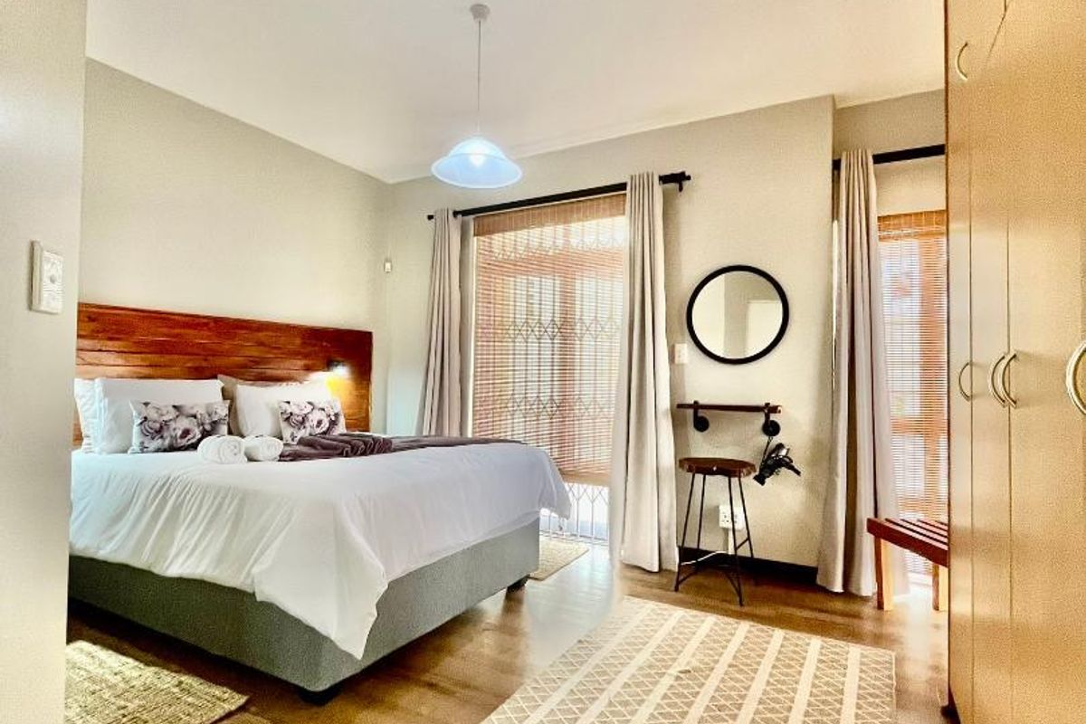 A well-maintained bedroom featuring built-in wooden cabinetry, timber-look flooring, and a feature timber headboard with integrated lighting.
