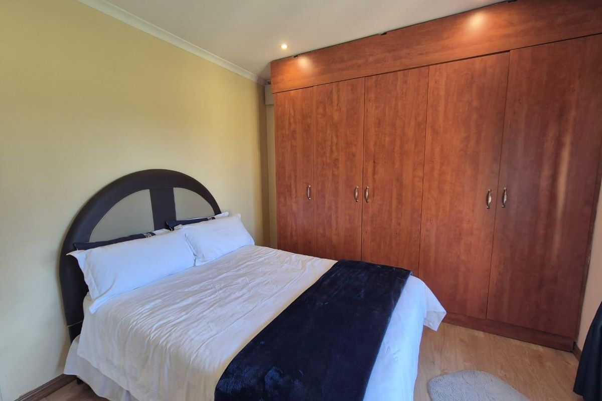 A bedroom featuring laminate flooring, recessed downlighting, and extensive floor-to-ceiling built-in wooden cupboards for storage.