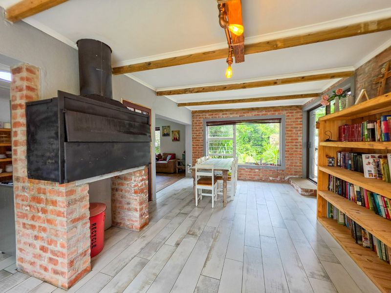 Spacious living area featuring exposed brick walls, timber ceiling beams, and a built-in fireplace, creating a rustic and inviting atmosphere.