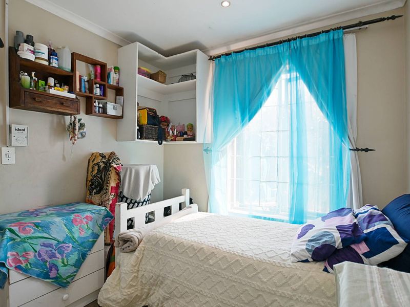 A bedroom featuring built-in corner shelving and recessed ceiling lighting, providing a functional space with natural light.