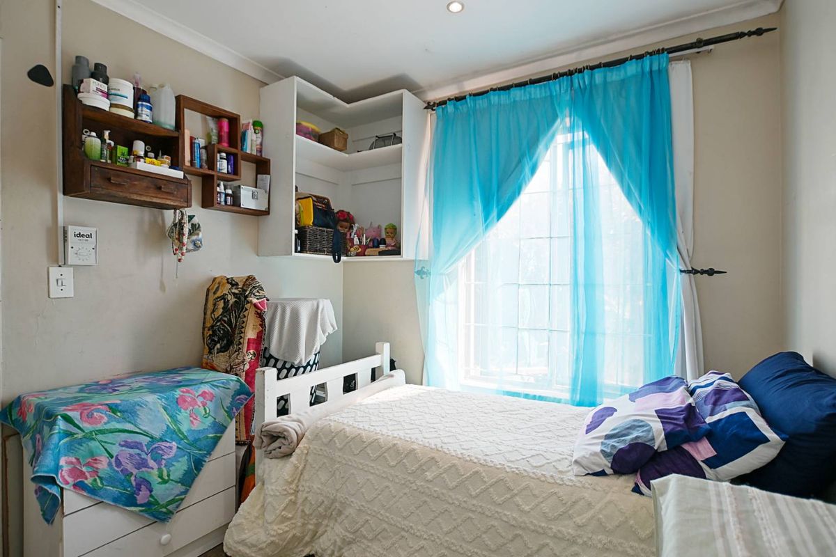 A bedroom featuring built-in corner shelving and recessed ceiling lighting, providing a functional space with natural light.