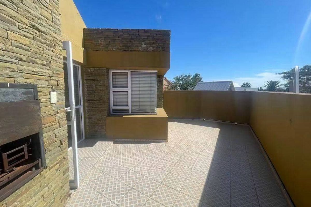Spacious outdoor patio featuring tiled flooring, stone cladding accents, and a built-in braai area, perfect for outdoor entertaining.