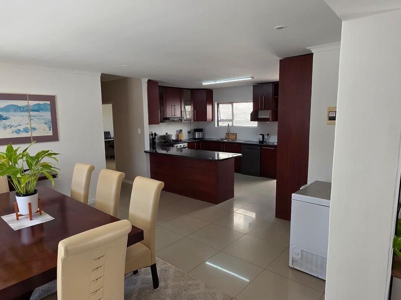 Open-plan living and dining area featuring a well-appointed kitchen with dark wood cabinetry, granite countertops, and modern built-in appliances.