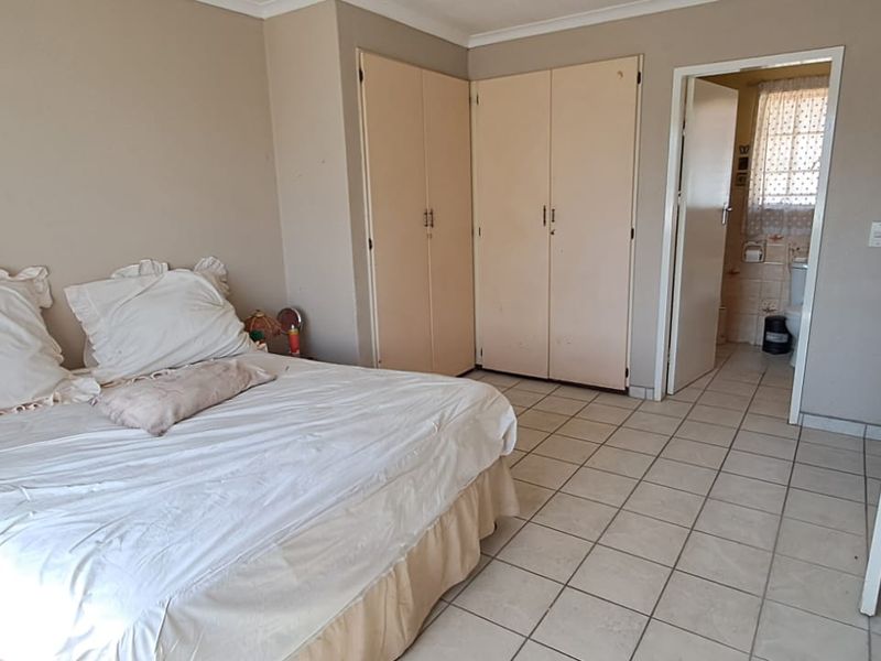A bedroom featuring tiled flooring, built-in cupboards, and direct access to an en-suite bathroom.