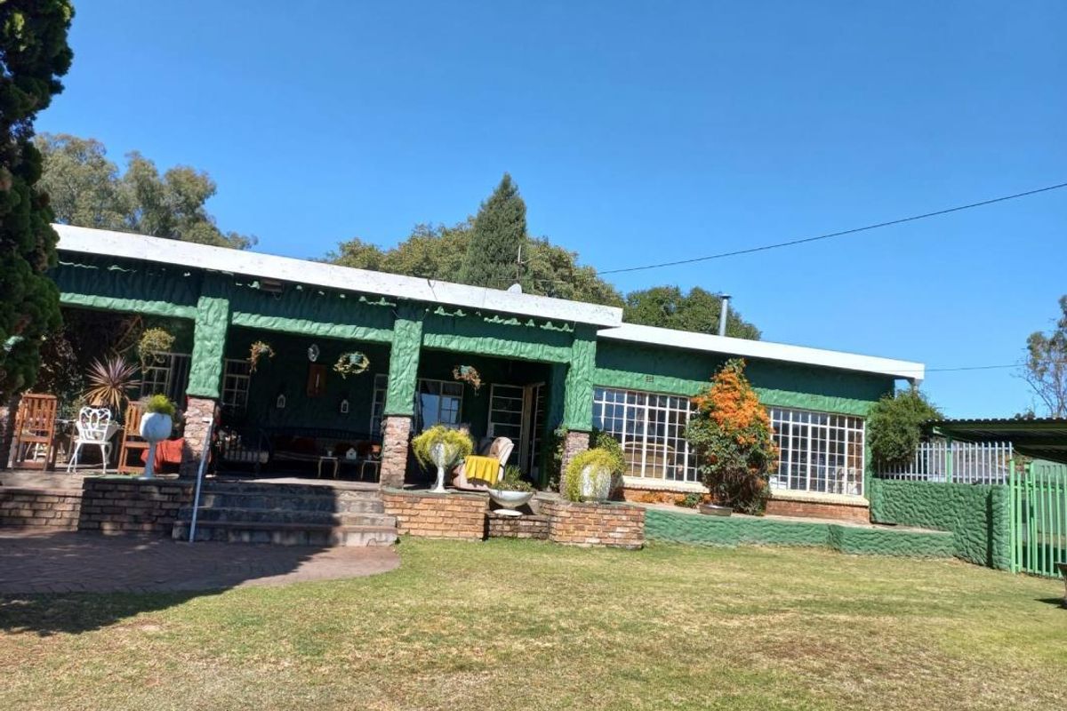Rear view of the property featuring a covered patio, brick stairs, and a spacious garden area with established landscaping.