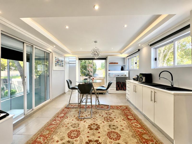 Bright open-plan living and kitchen area featuring modern cabinetry, recessed ceiling lighting, and large sliding glass doors leading to an outdoor space.