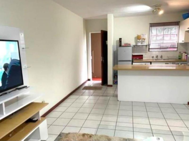 Open plan living area featuring a kitchen with breakfast bar and tiled flooring throughout.