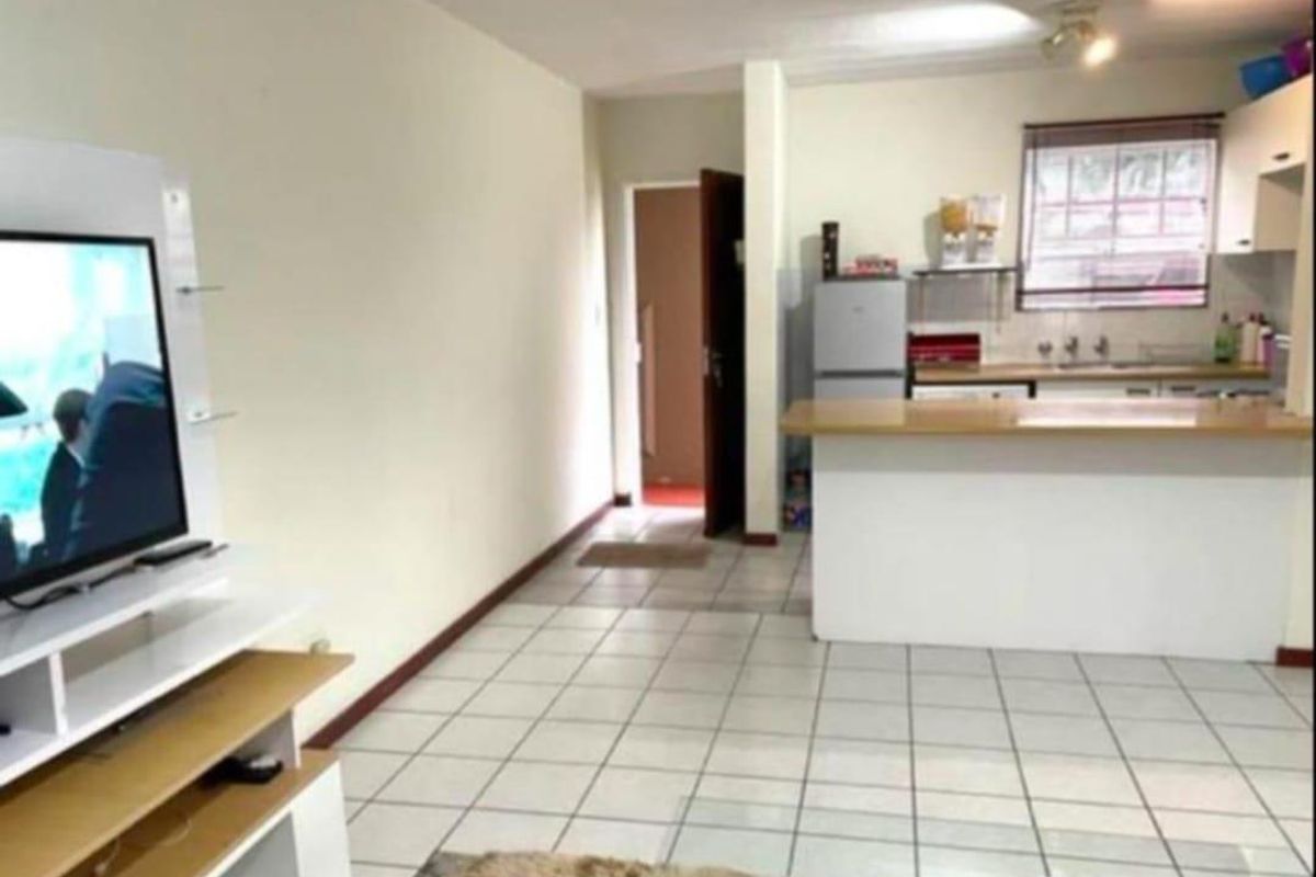 Open plan living area featuring a kitchen with breakfast bar and tiled flooring throughout.